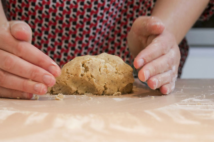 Midsection of woman kneading dough on table