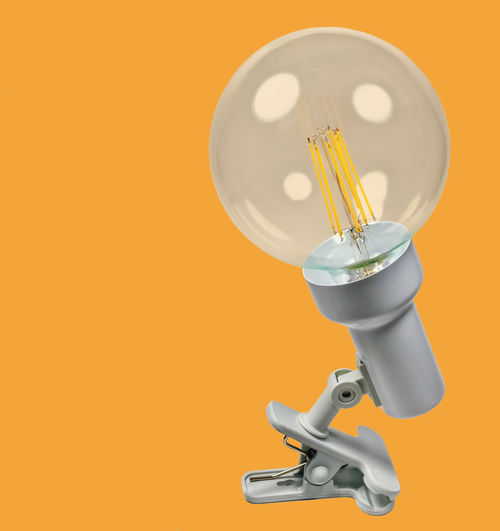 Close-up of light bulb against orange background