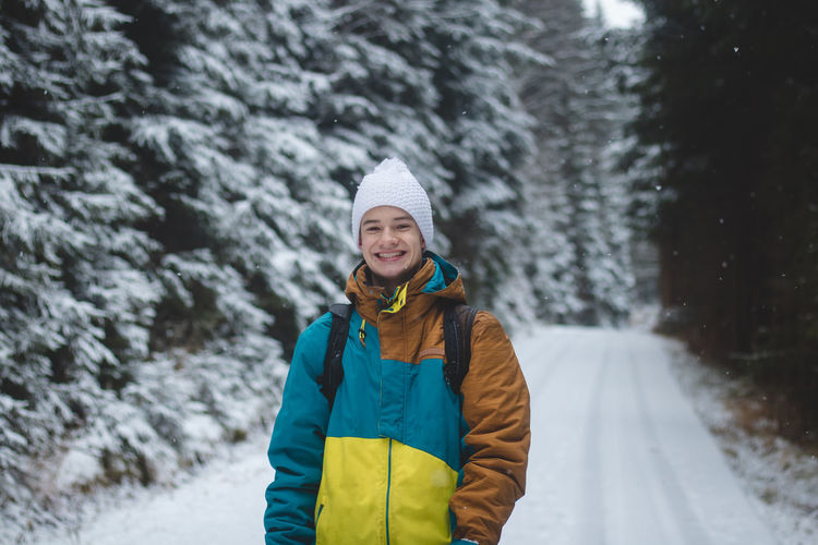 Candid portrait of smiling young man wearing winter jacket during the winter season in a snowy area
