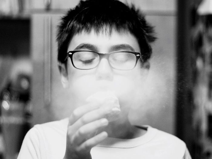 Close-up of boy blowing powdered sugar on donut at home