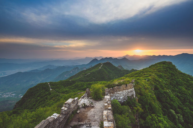 Scenic view of mountains against cloudy sky during sunset