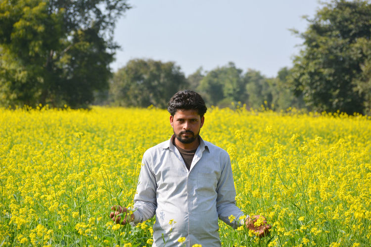 Young indian farmer at black mustard field