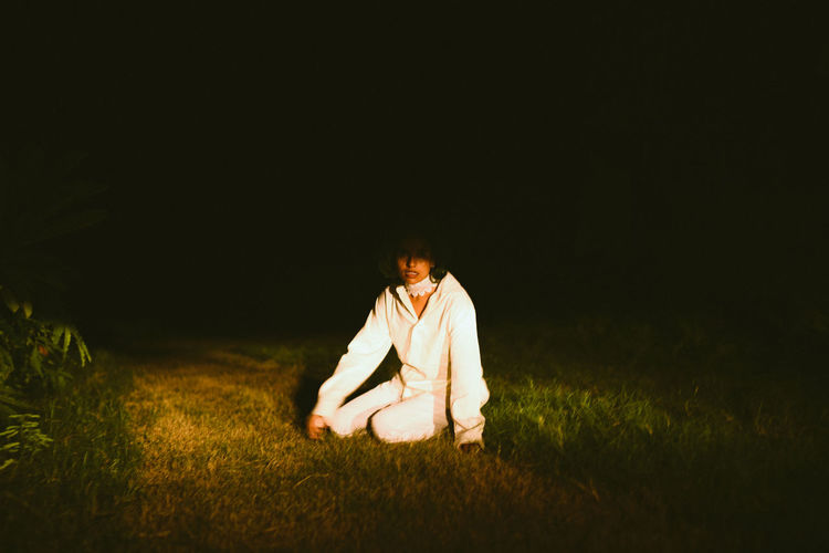 Woman sitting on field at night