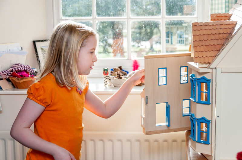 Side view of girl holding window at home