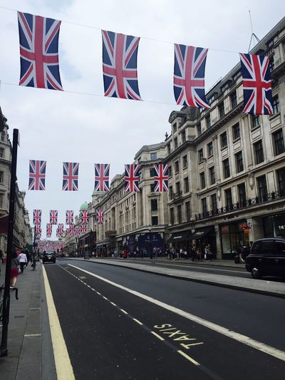 British flags handing over road against cloudy sky