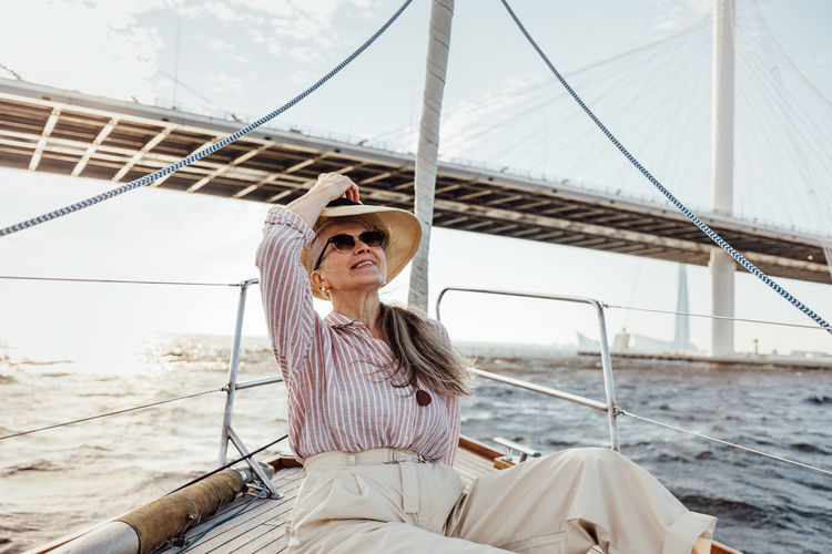 YOUNG WOMAN SITTING ON SAILBOAT