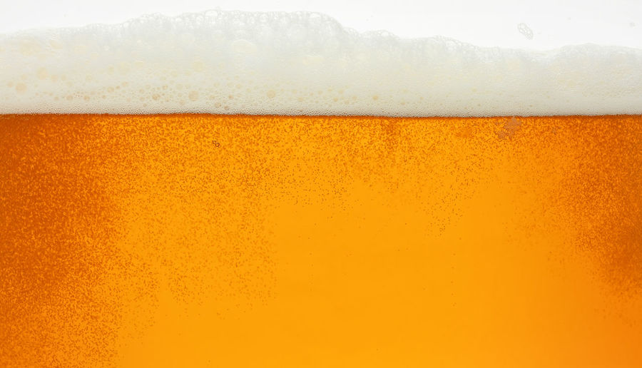 Full frame shot of beer on glass against orange sky