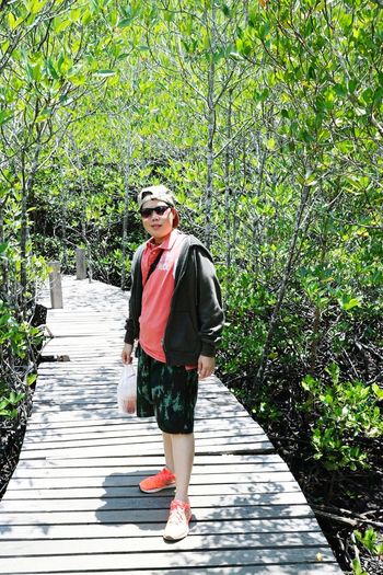 Portrait of mid adult man wearing sunglasses standing on footpath in forest