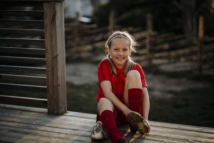 Portrait of smiling girl sitting on wood