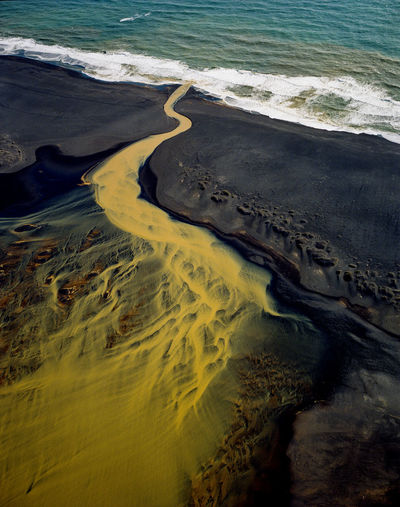 Aerial view of braided orange river flowing into ocean in southe