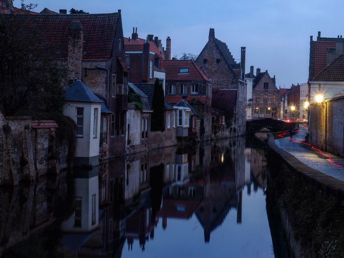 Buildings by canal in city at dusk