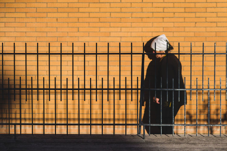 Man standing by railing against orange wall