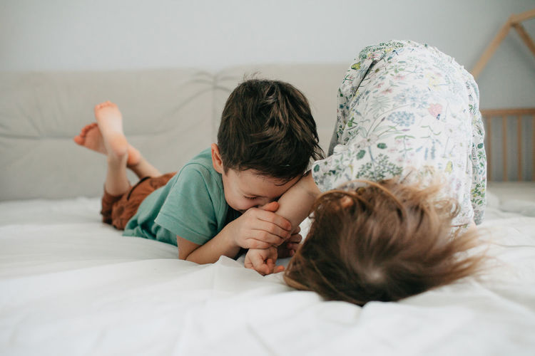 Older brother and younger sister playing in the bedroom on the bed. high quality photo