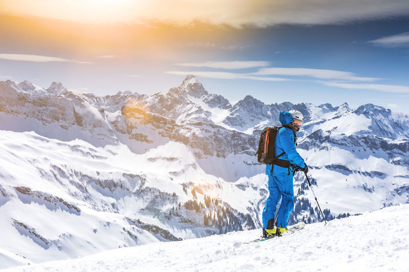 Man standing on snowcapped mountain against sky