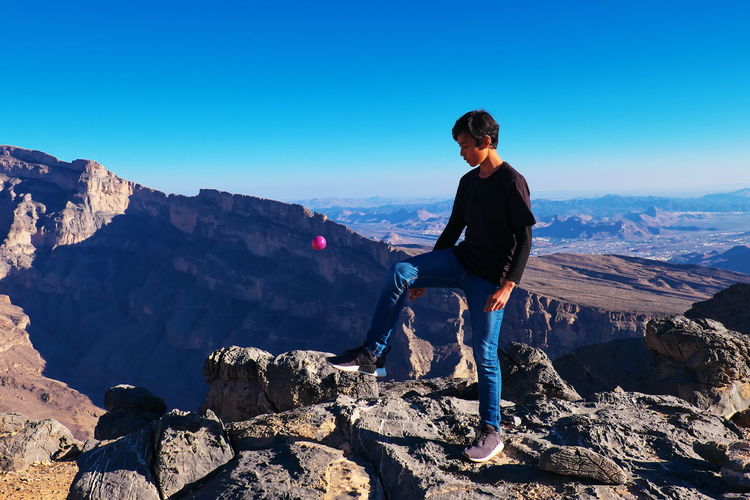 Full length of teenage boy standing on mountain against sky