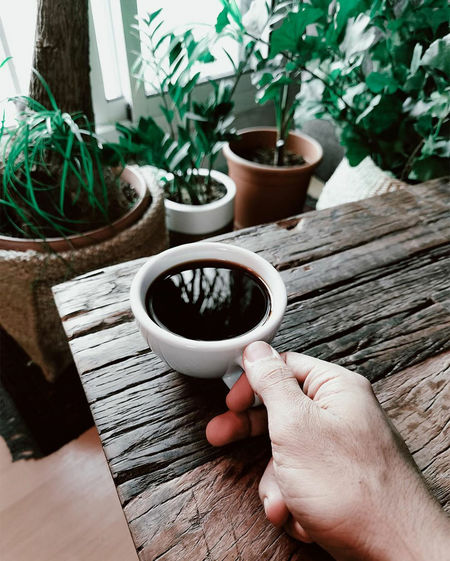 Cropped image of person holding coffee cup on table
