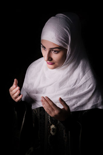 High angle view of woman in burka gesturing during praying