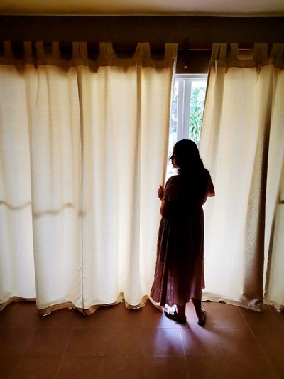High angle view of woman standing by window at home