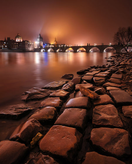 River by illuminated city against sky at night