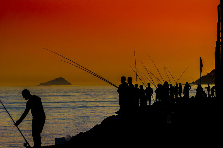 Silhouette people at fishing during sunset