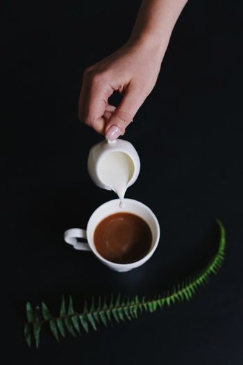 Hand holding coffee cup against black background