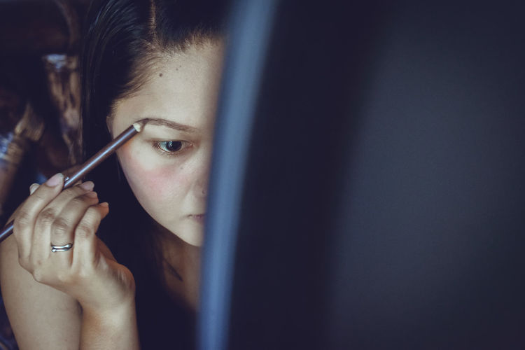 Portrait of woman putting mascara on eyebrow