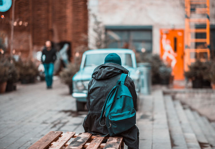 Rear view of person walking on footpath against buildings