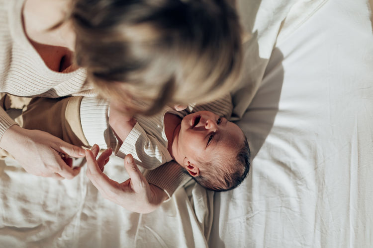 Top view smiling newborn baby in mom's arms warm daylight