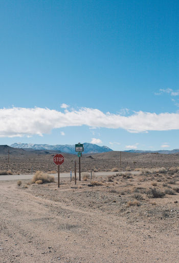 Road sign in desert against blue sky