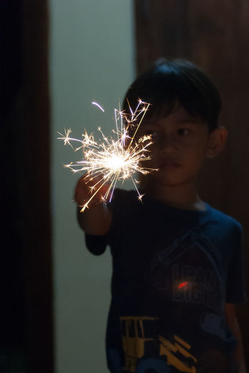 Young woman holding sparkler at night