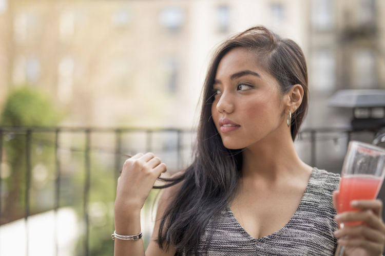 Young woman with a cocktail on her balcony