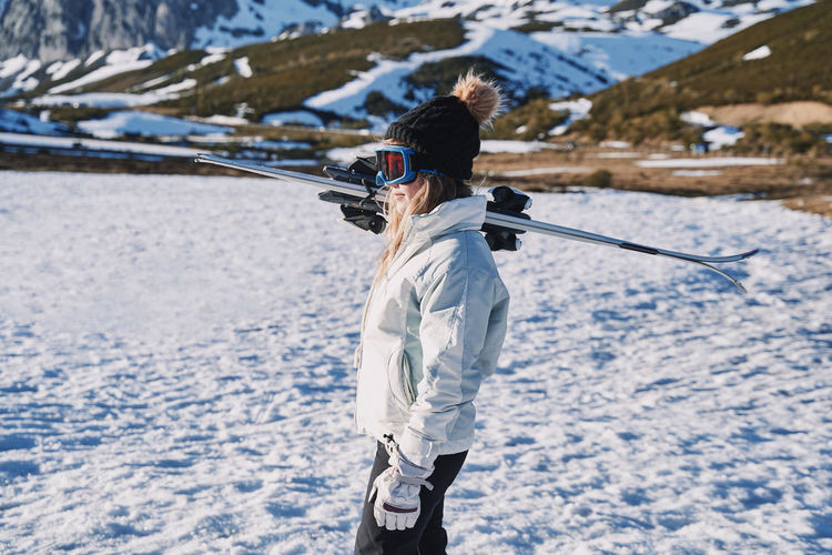 Woman wearing ski goggles while standing on snow covered land