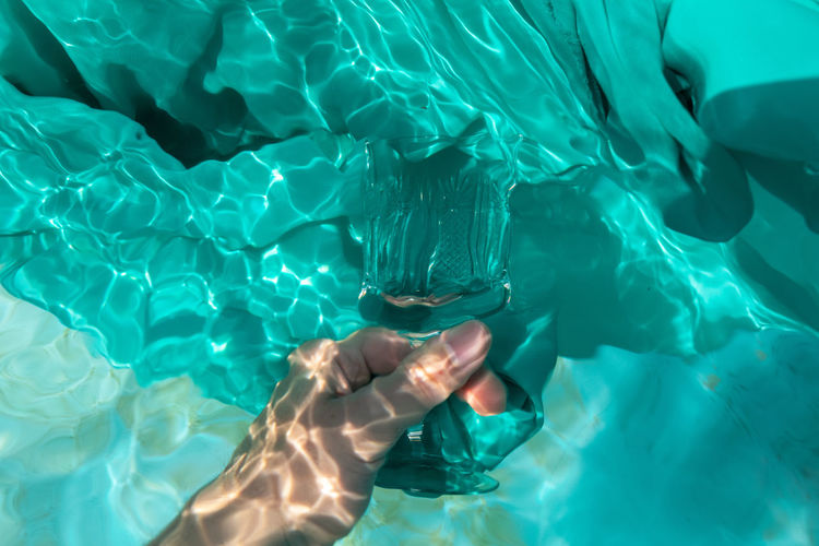 Cropped hands of woman holding prism in swimming pool