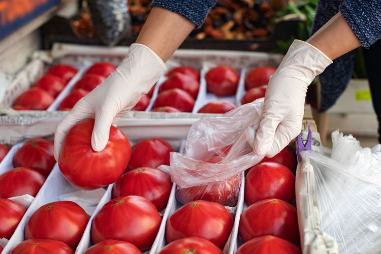 The concept of safe shopping. buying products  a woman in disposable gloves buys tomatoes