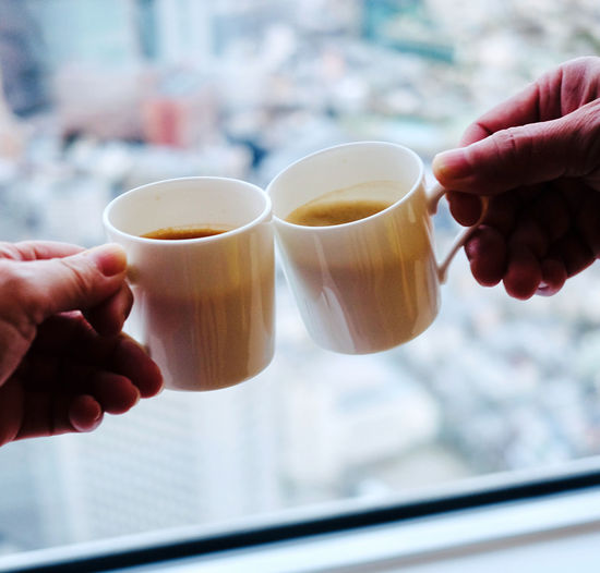 Cropped image of two persons holding coffee cup