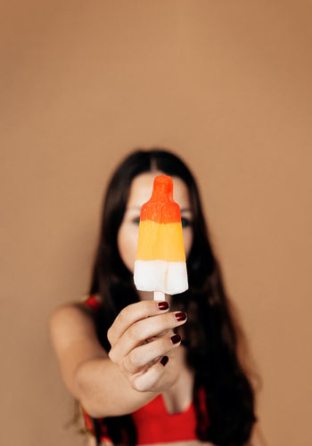 Focus on the hand of a brunette girl holding a popsicle. vertical picture