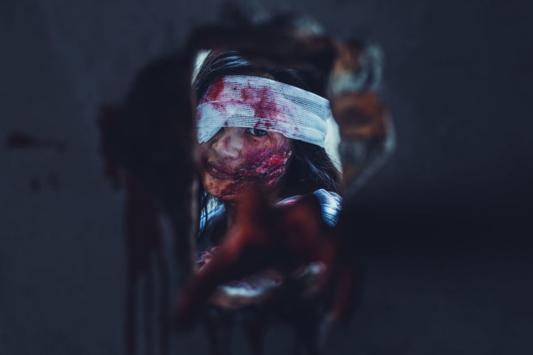 Portrait of wounded woman looking through hole