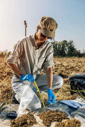 Agronomist writing in paper while crouching on field