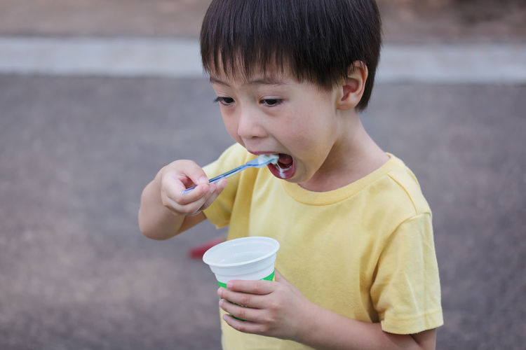 Close-up of boy eating ice cream on road