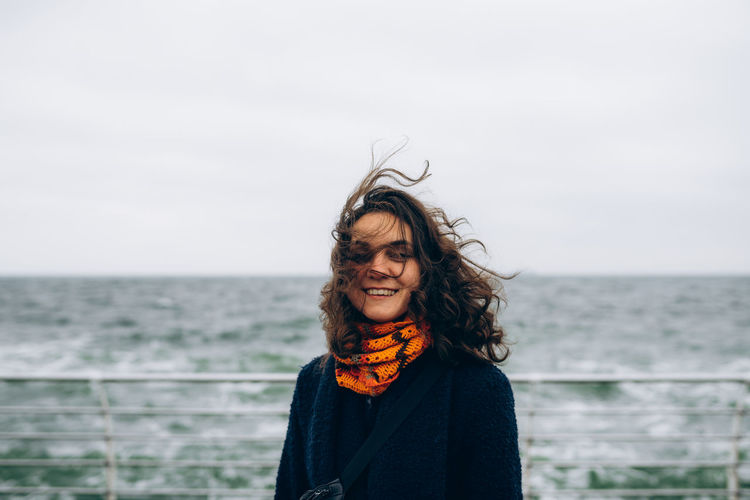 Portrait of happy smiling woman walking outdoor in the sea shore beach on wind weather. person