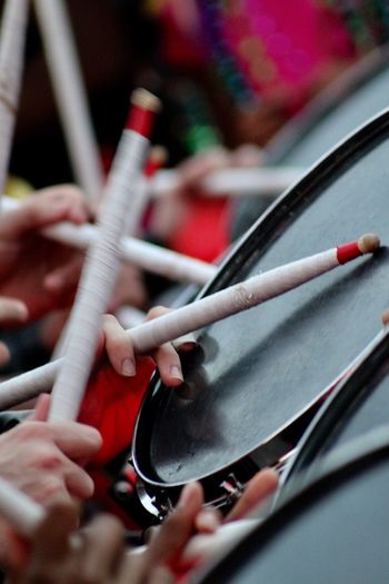 Cropped image of people playing drum with stick