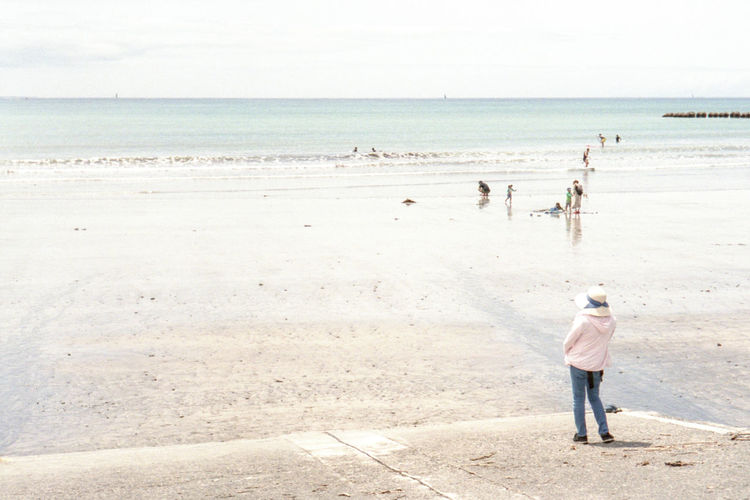 Rear view of man standing at beach against sky