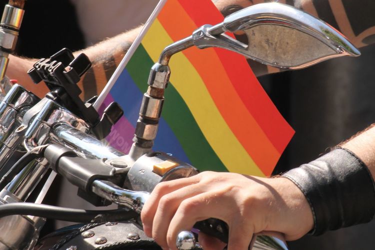 Cropped image of man riding motorcycle with rainbow flag