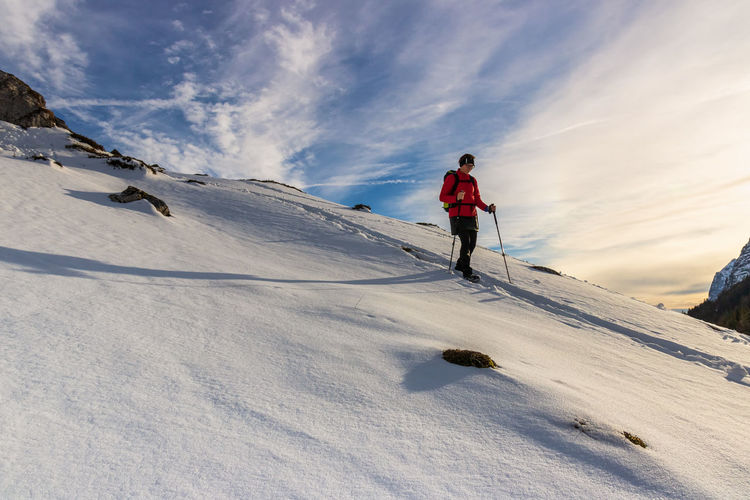 Low angle view of person hiking on snow covered land