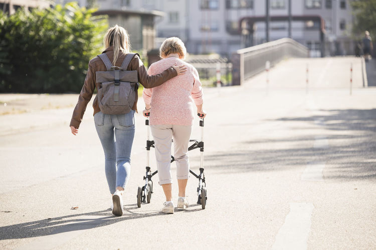 Granddaughter assisting her grandmother walking with wheeled walker