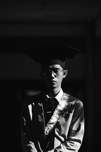 Portrait of young man standing against dark