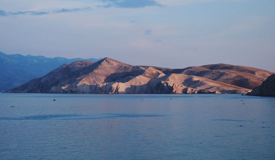 Scenic view of sea and mountains against sky