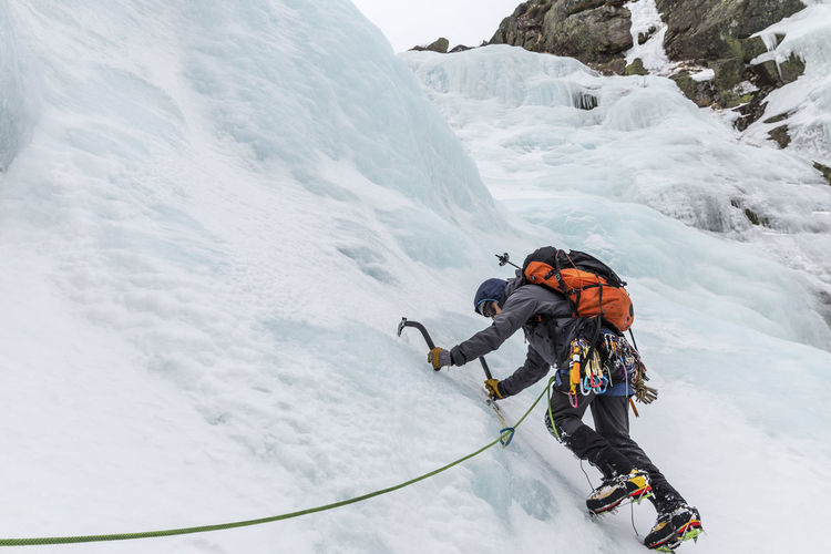 Full length of backpacker ice climbing at white mountains during winter