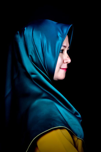 Portrait of young woman against black background