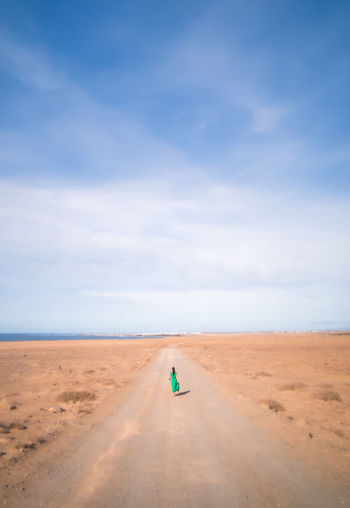 Mid distance view of woman walking on road at desert